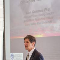 Man speaking in front of a presentation at Naples 2019. The projection on the screen reads "Our Great Lakes: Challenges and Solutions."